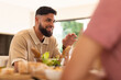 © wavebreak3 - Smiling man enjoying conversation with diverse friends over meal at dining table
