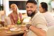 © WavebreakMediaMicro - Smiling man enjoying meal with diverse friends at dining table, having good time