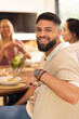 © wavebreak3 - Smiling man enjoying meal with diverse friends, sitting at dining table, socializing