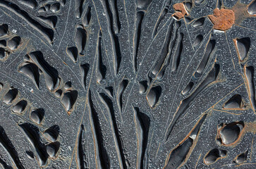 Dark background, Abstract pattern of swollen bubbles of different shapes of old black paint on a metal rusty surface, looks like abstract art