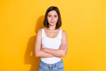 Wall Mural - Photo portrait of attractive young girl crossed hands confident wear trendy white outfit isolated on yellow color background