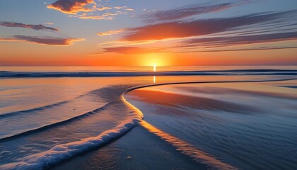 Wall Mural - Tranquil beach sunset with soft waves creating a gentle curve on the shore, mirroring the orange glow of the setting sun in peaceful waters.