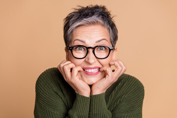 Wall Mural - Photo of horrified woman with short hairdo dressed khaki sweater in glasses biting fingers staring isolated on beige color background