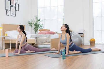 Two asian women stretching on yoga mat