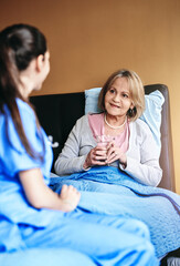 Wall Mural - Elderly, woman and nurse with drinking medication at retirement facility for healthcare and prescription drugs. Senior, patient or caregiver in nursing home with pills, support and water for wellness