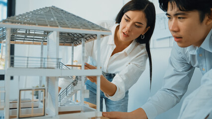 Wall Mural - Closeup of young professional skilled architect engineer team focusing on checking the house model structure at modern office. Creative professional design and teamwork concept. Immaculate.