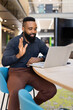 © wavebreak3 - Waving and smiling, African american man having video call on laptop in modern office