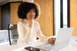 © wavebreak3 - Smiling woman working on laptop at office desk with smartphone nearby