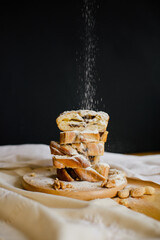 Homemade pie, sweet dessert with chocolate and nuts, cut into chunks. A wooden plate and a textured wooden table. A black wall on a background and a linen tablecloth. The comfort of home. Rustic