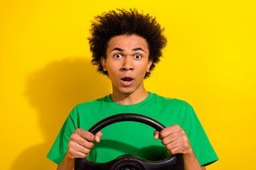 Photo of handsome impressed guy wear green t-shirt riding car emtpy space isolated yellow color background