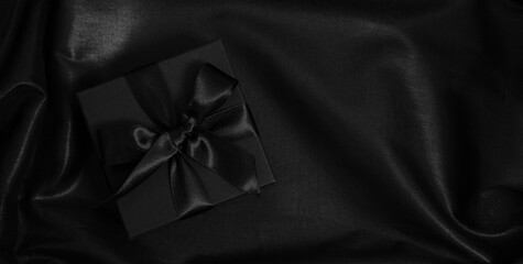 Wall Mural - Black Friday sale banner. Gift box with ribbon and bow on black satin, top view