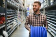 © Serhii - male plumber in a hardware store chooses the sewer pipes, the concept of plumbing work in the house