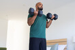 © Wavebreak Media - Lifting dumbbells, man exercising at home for strength training workout