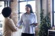 © Wavebreak Media - Shaking hands, businesswomen discussing project with tablet in modern office