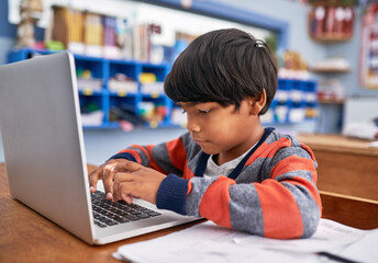 Laptop, kids and boy in classroom for lesson in growth, child development and technology for education. Desk, learning and students with website for knowledge, typing and study at elementary school