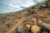 Rocky terrain on a hillside with scattered stones under a cloudy sky in a desert landscape during late afternoon