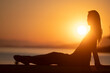 © Gajus - Profile view of a young woman sitting by the sea at beautiful sunrise