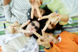© Seventyfour - Top view of four teenage friends lying on picnic blanket joining hands in star shape while hanging out outside in park enjoying time together, copy space