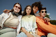 © Seventyfour - Medium portrait shot of four smiling teenagers from different ethnic backgrounds happily posing together while sitting outside in sunshine enjoying summertime in park, fisheye effect, camera flash