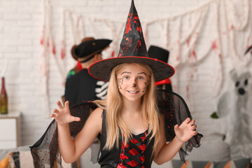 Wall Mural - Cute happy girl dressed as witch for Halloween party with friends at home