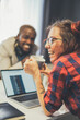 © Svyatoslav Lypynskyy - A woman with glasses and a red plaid shirt is smiling while holding a coffee cup. She is sitting next to a laptop computer