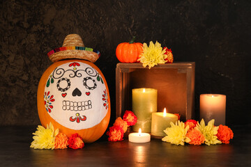 Poster - Pumpkin with painted skull, mini sombrero, burning candles and flowers on dark background. El Dia de Muertos