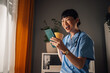 © Zamrznuti tonovi - Asian woman nurse standing by window, with phone and yellow patterned mug