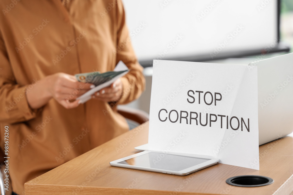 Paper with text STOP CORRUPTION on teacher's table in classroom, closeup. Corruption concept