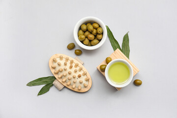 Wall Mural - Bowls with green olives, oil and massage brush on grey background