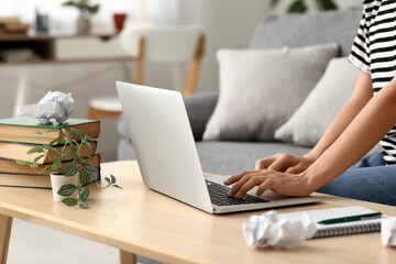 Wall Mural - Beautiful female writer with laptop, notebook and books sitting on sofa at home, closeup