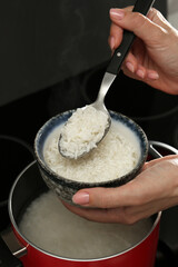 Wall Mural - Woman taking boiled rice from pot into bowl, closeup