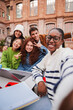 © Jose Calsina - Vertical. African american teenage student taking a selfie with her friends using a smart phone. Group of multiracial classmates taking a portrait with a cellphone at the university campus meeting