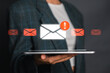© Satori Studio - Digital envelope with exclamation mark symbolizing e-mail security warning notification, held by a person in a suit.