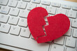 © pla2na - Red broken heart on white keyboard computer background. Online internet romance scam or swindler in website application dating concept. Love is bait or victim.