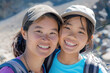© KirKam - Asian mother and daughter smiling brightly during a hiking adventure, showcasing family bonding and outdoor enjoyment