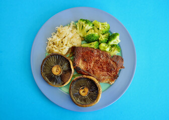 A porterhouse steak with mushrooms broccoli and sauerkraut.