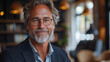 © Vertigo Images - Smiling mature man wearing glasses in a cafe.