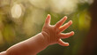 © Mutshino_Artwork - Baby's hand reaching out with soft natural lighting and blurred background