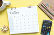 © Yuphayao Pooh's - Top view of January 2025 calendar. January 2025 calendar and pen, notebook, coffee cup on yellow background. Happy new year 2025 concept