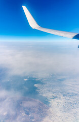 Wall Mural - View from the airplane window at a beautiful blue clear sky, earth, sea and the airplane wing