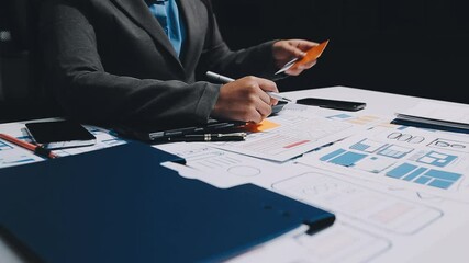 ux developers and ui designers, data researchers brainstorm on tabletop mobile app interface wireframe design with client summary color codes the modern office Creative Digital Development Agency.