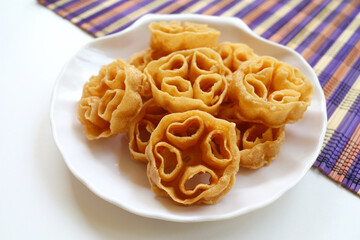 Traditional Indonesian Crackers, Kembang Goyang or shaking flower served on a white plate. Indonesian typical homemade crispy fried snack in flowers shape.