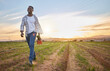 © peopleimages.com - Happy, field and walking with black man on farm for organic, sustainability and growth. Sunset, agriculture and food security with person in countryside for nature, summer ecology and environment