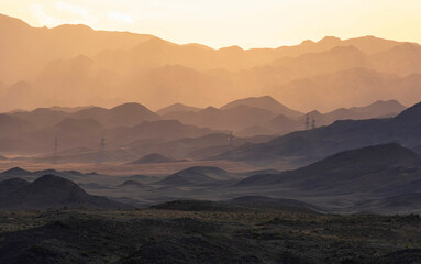 Desert mountains in gradient haze in warm yellow and brown colors at sunset