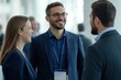 © Surachetsh - A lively conversation between three suited professionals at a trade fair, their staff lanyards visible, reflecting the collaborative and laid-back nature of corporate networking events.
