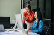 © laddawan - ￼￼Two young Asian professionals engaged in teamwork and business discussions in modern office