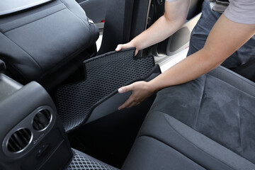 Wall Mural - Man taking grey rubber car mat from auto, closeup