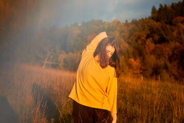 a portrait  young woman in mustard sweater in autumn mountains at sunset