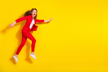 Poster - Full size photo of pretty young woman jump rush empty space wear red suit isolated on yellow color background