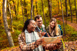 © Zoran Zeremski - Three friends having fun and enjoying hiking in forest using map for direction.